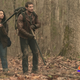 The Walking Dead: World Beyond's Aliyah Royale and Nico Tortorella stay ready in a forest with weapons in hand.